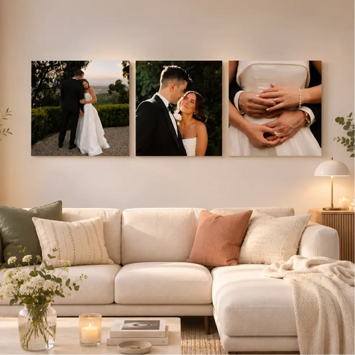 Un set triptico de tres lienzos cuadrados de boda personalizados, con fotos de la pareja, primeros planos de manos con anillos y la novia, montados sobre un sofá seccional beige.
